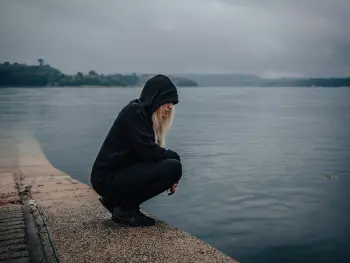 Frau schaut traurig ins Wasser